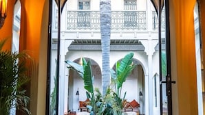 A lobby with a checkered floor, large potted plants, and a central fountain. - RIAD XO (Marrakech)