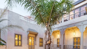 A courtyard with a palm tree, checkered floor, and balconies with ornate railings. - RIAD XO (Marrakech)