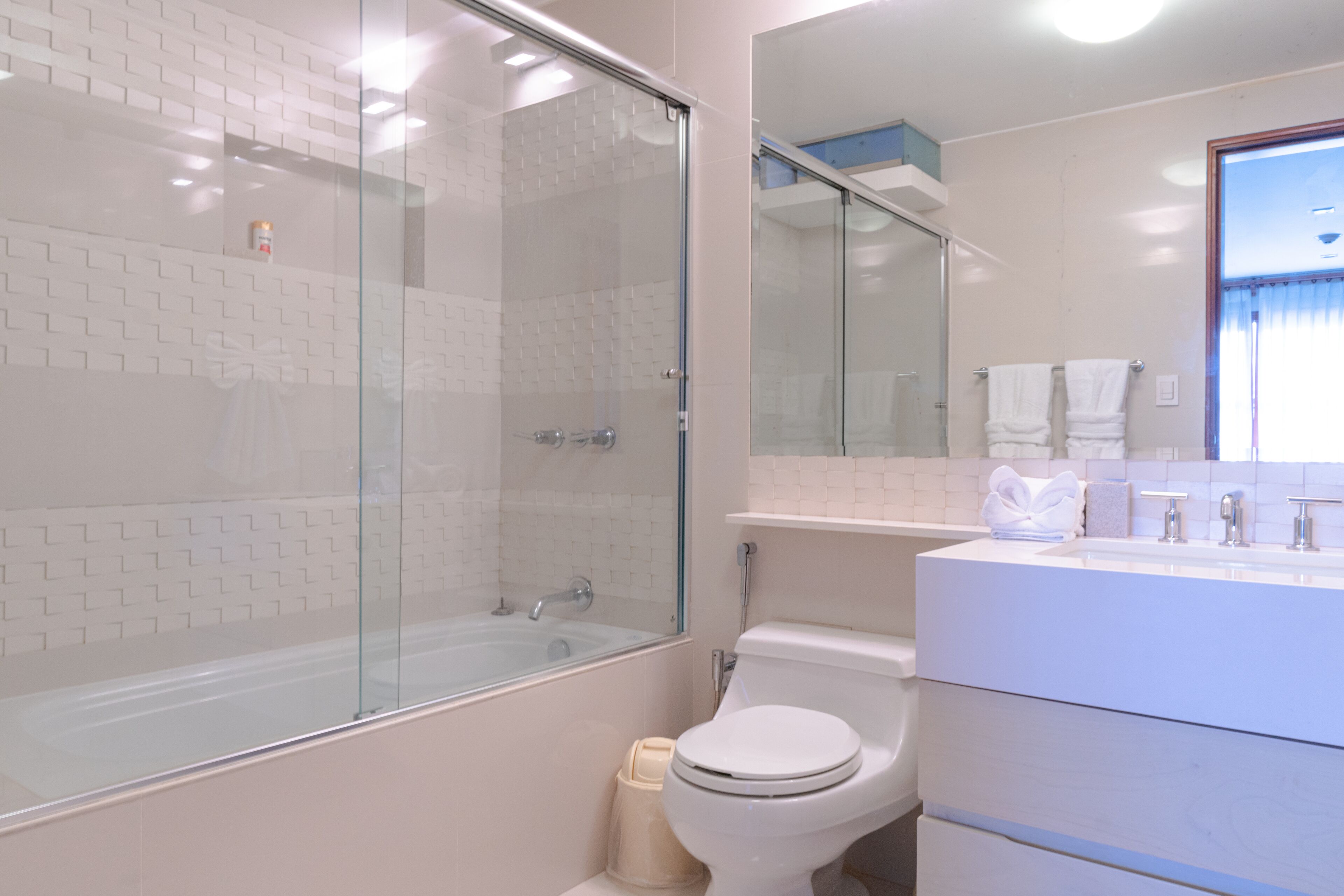 A modern bathroom with a glass-enclosed shower, a white toilet, and a vanity with a mirror.