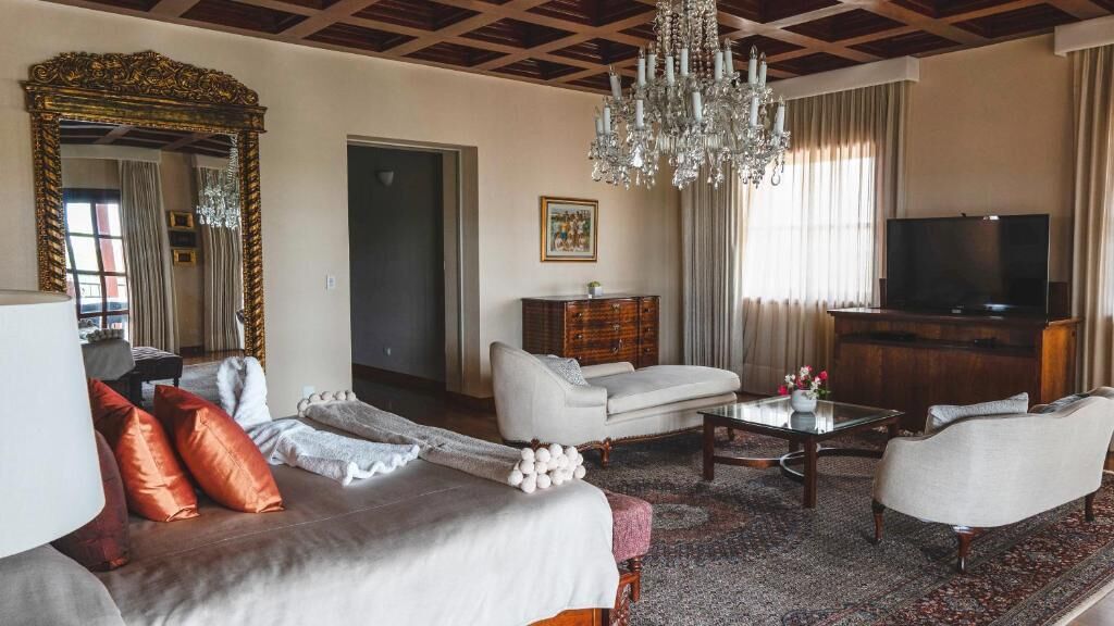 A living room with a sofa, armchairs, a coffee table, a TV, a chandelier, and a large mirror.