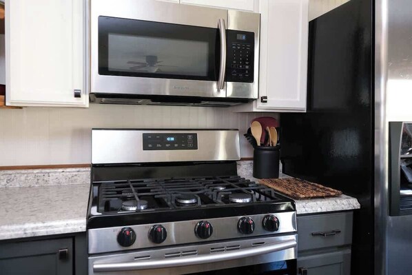 A kitchen with stainless steel appliances, including a microwave and stove, and a black refrigerator.