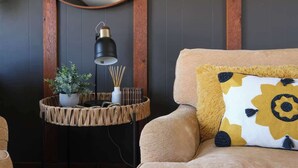 A cozy room with a round mirror, a lamp, a woven side table with a potted plant, and a sofa with a patterned pillow. - 3BR Sleep 6 PALO DURO CANYON Bunker Cabin Pet OK (Canyon)