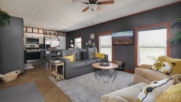 A modern living room with a gray sofa, a beige sofa, and a coffee table. There is a kitchen in the background with a microwave and a refrigerator. - 3BR Sleep 6 PALO DURO CANYON Bunker Cabin Pet OK (Canyon)