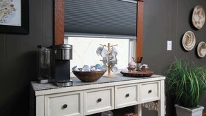 A kitchen counter with a coffee maker, a bowl, and a window with blinds. - 3BR Sleep 6 PALO DURO CANYON Bunker Cabin Pet OK (Canyon)