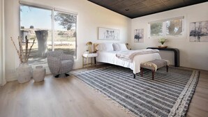 A bedroom with a bed, a chair, a bedside table, and artwork on the walls. - 3BR Sleep 6 PALO DURO CANYON Cabin + WTAMU Trails (Canyon)