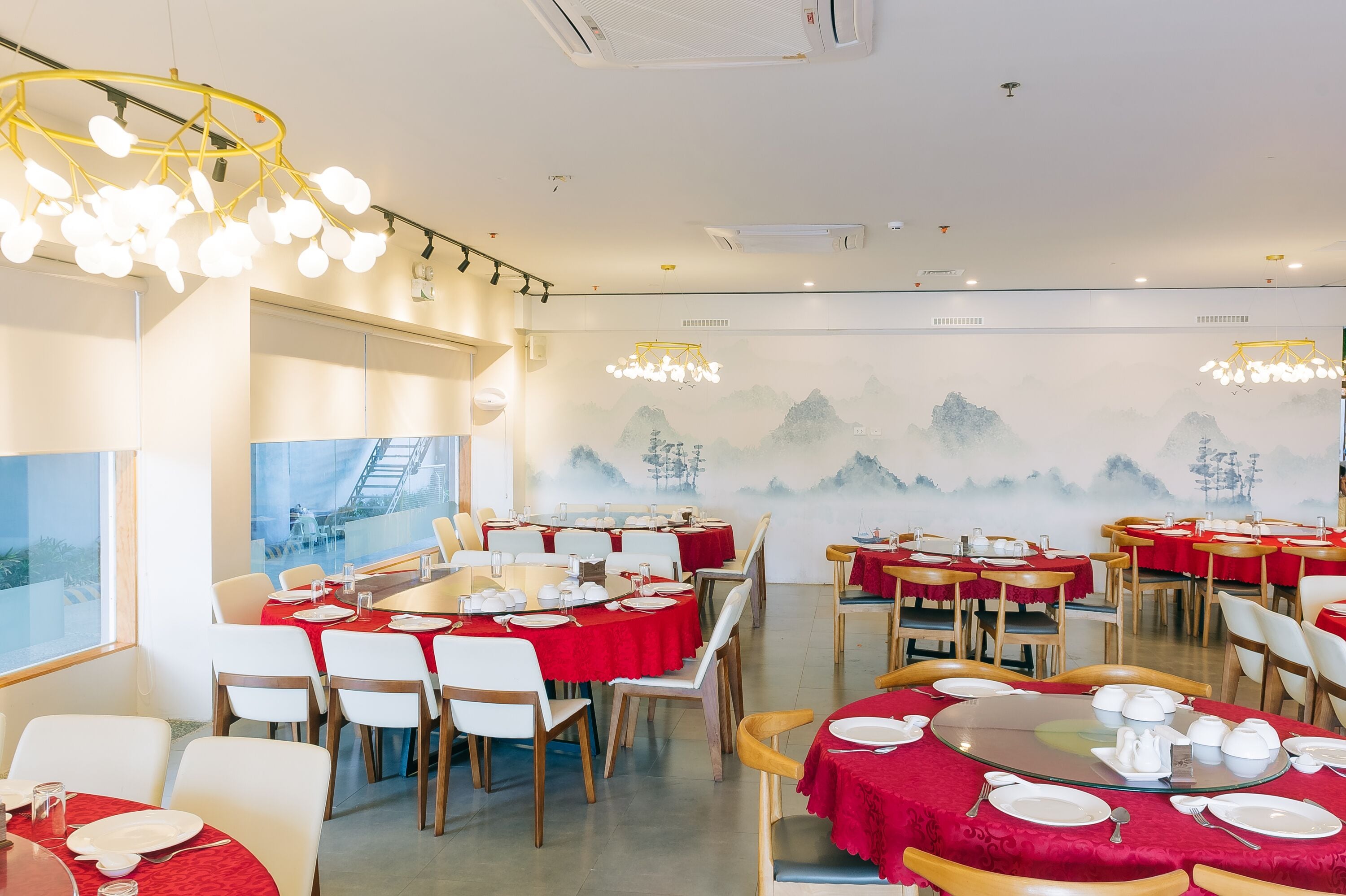 A restaurant with round tables, red tablecloths, and traditional decor.
