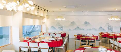 A restaurant with round tables, red tablecloths, and traditional decor.