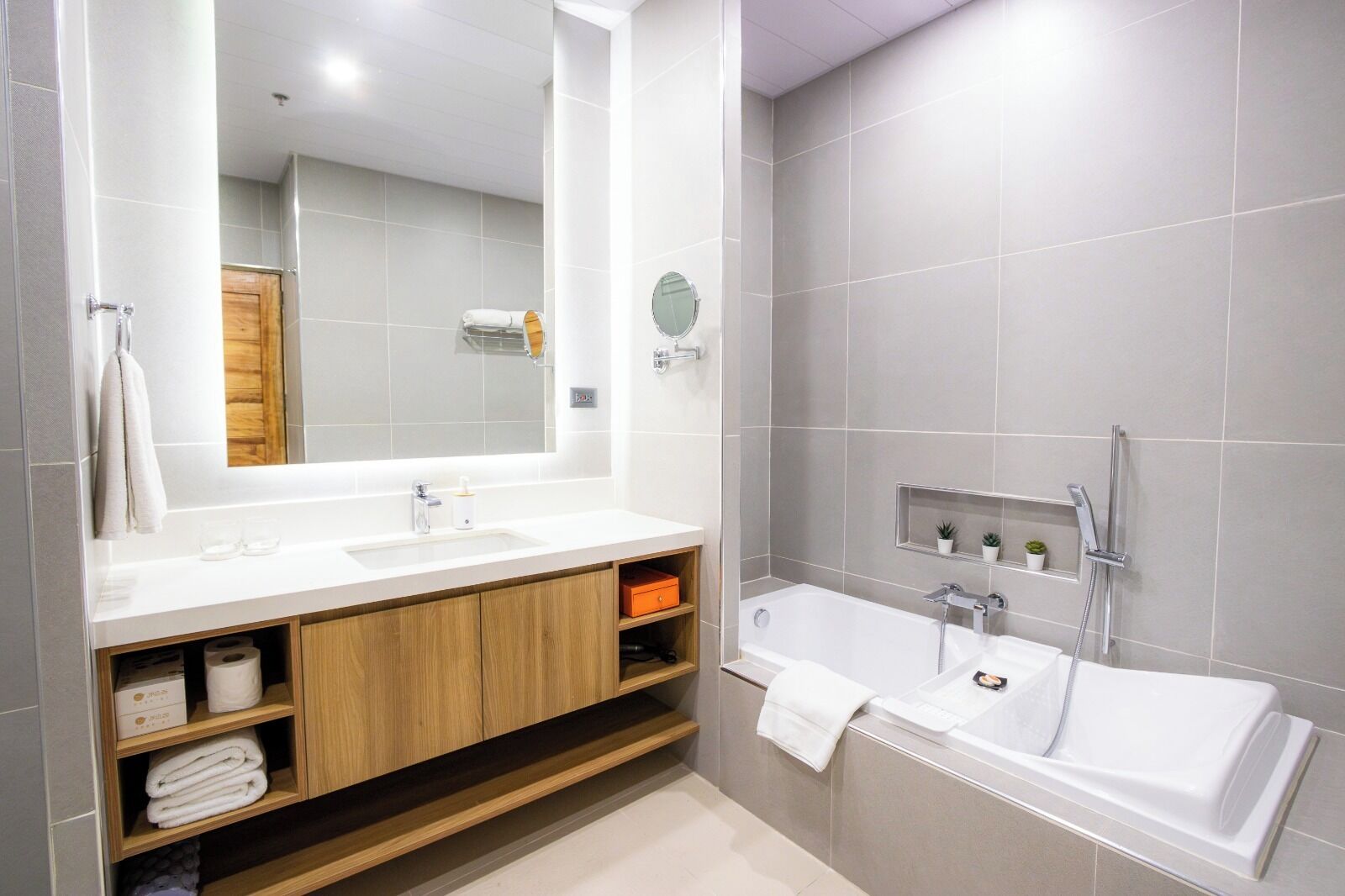 Un baño moderno con un espejo grande, dos lavamanos, una ducha y un mueble de tocador de madera con espacio de almacenamiento.