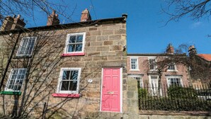 A stone building with a red door and multiple windows. - Red Grouse Cottage (Guisborough)