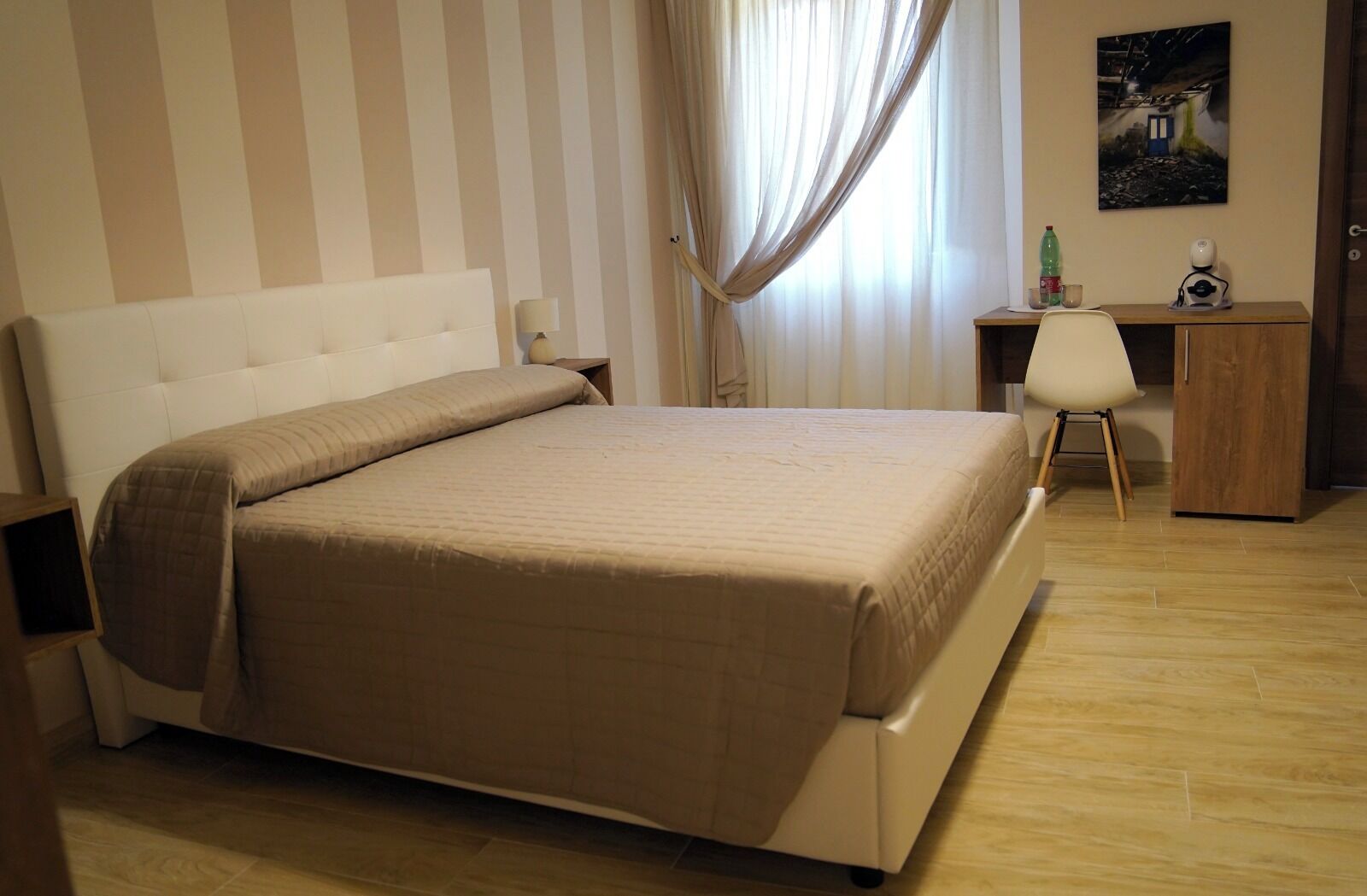 Una habitación de hotel ordenada con una cama grande, un escritorio y una silla.