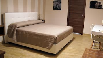 A bedroom with a bed, a desk, and a door.