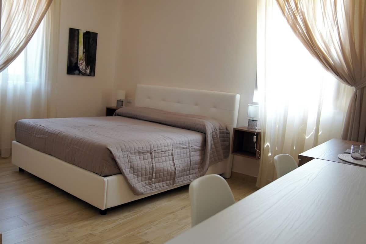 A bedroom with a bed, bedside table, and a chair.