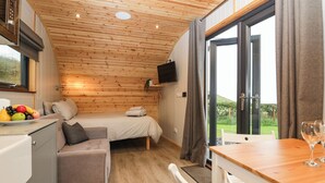 A cozy cabin-style room with a bed, a small sofa, a dining table, and a kitchen area. - Forest (Dalton-in-Furness)
