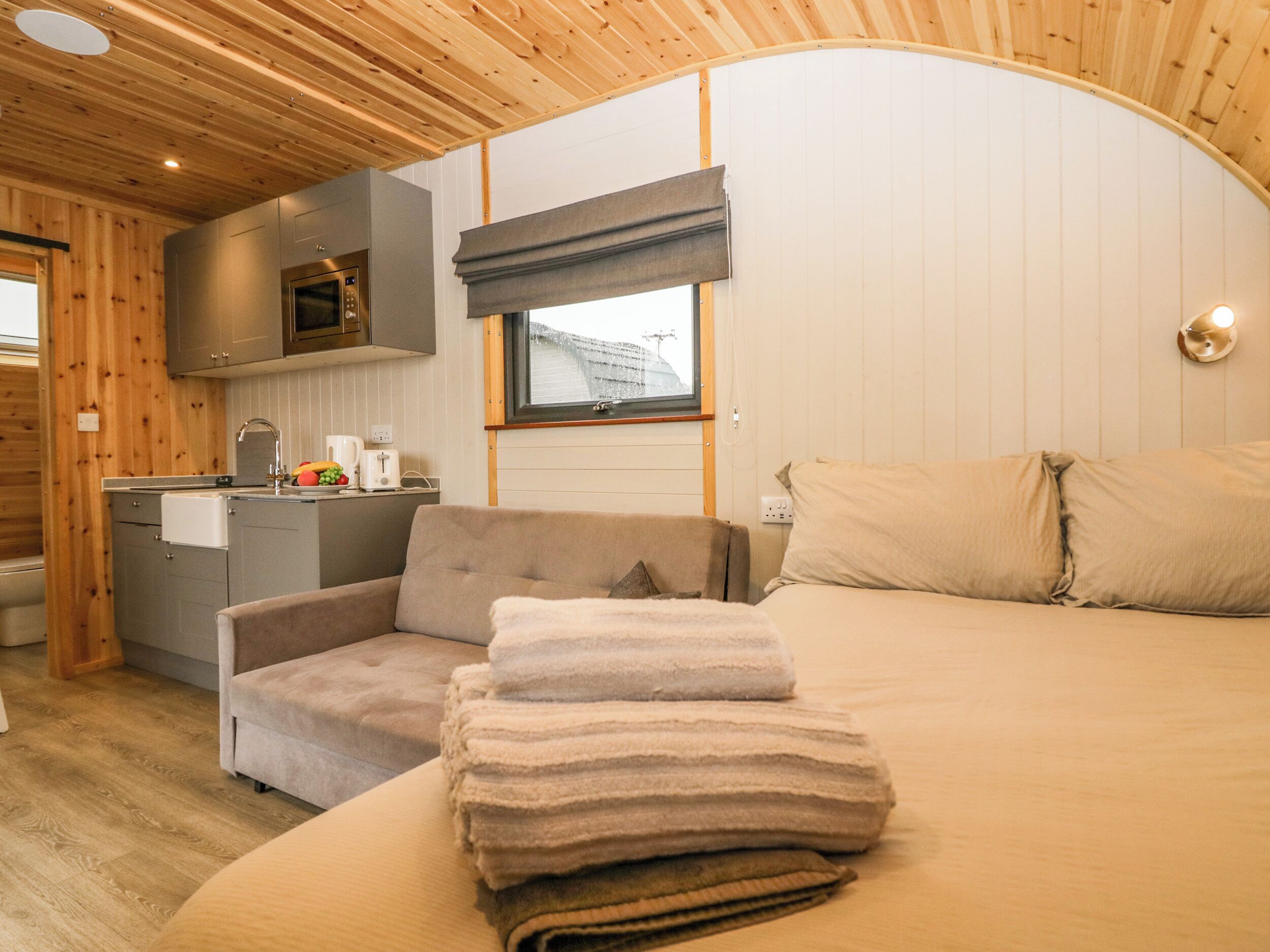 A compact, modern cabin interior with a kitchenette, a sofa, and a bed.