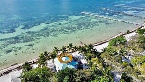 A beachside resort with a pool, palm trees, and clear blue water.