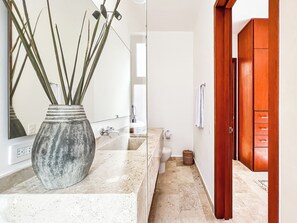A bathroom with a large mirror, a sink, and a wooden door.