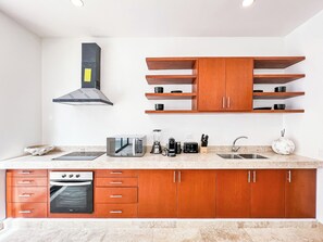 A modern kitchen with wooden cabinets, a built-in oven, a microwave, and a coffee maker.