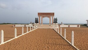 Una playa con una cerca blanca que conduce a una estructura con un arco.