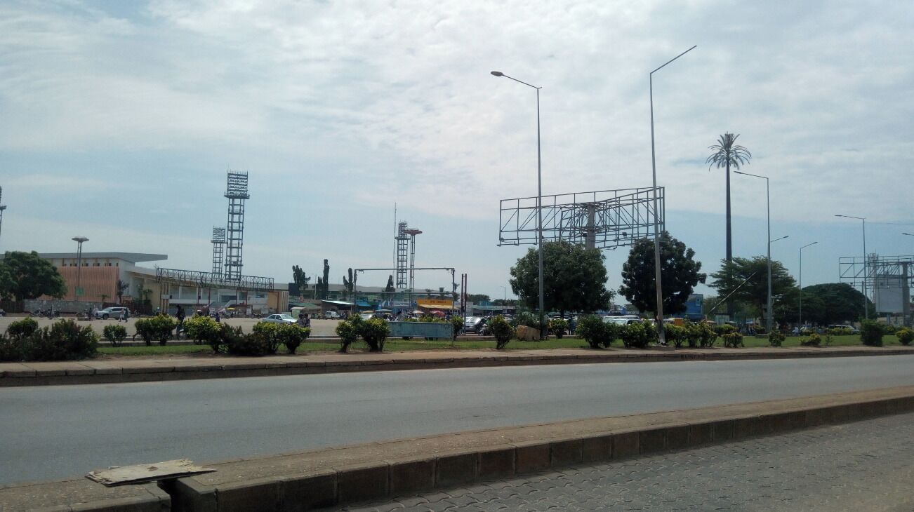 A road with a median strip, street lamps, and a large billboard structure.