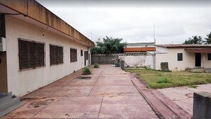 Un patio con un sendero empedrado, un edificio con rejas en las ventanas y un pequeño jardín.