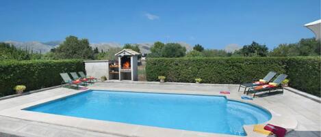 A rectangular swimming pool with a hot tub and lounge chairs.