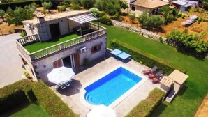 A two-story house with a swimming pool, a covered patio, and a well-maintained lawn. - Villa Poley (IB)