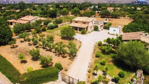 A rural village with traditional stone houses, a central paved road, and surrounding greenery. - Villa Poley (IB)