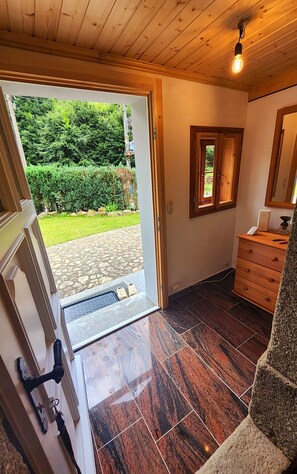 A room with a wooden door leading to a garden, a small wooden dresser, and a tiled floor. - Peace and relaxation in Saxon Switzerland (Sebnitz)