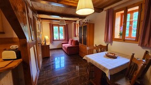A cozy room with a wooden ceiling, a dining table with chairs, a red sofa, and a window with curtains. - Peace and relaxation in Saxon Switzerland (Sebnitz)