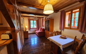 A cozy room with a wooden ceiling, a dining table with chairs, a red sofa, and a window with curtains. - Peace and relaxation in Saxon Switzerland (Sebnitz)