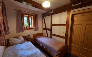 A bedroom with a bed, a nightstand, a lamp, and a window with curtains. - Peace and relaxation in Saxon Switzerland (Sebnitz)