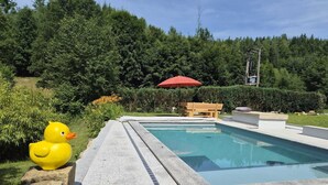 A swimming pool with a wooden bench and a red umbrella. - Peace and relaxation in Saxon Switzerland (Sebnitz)