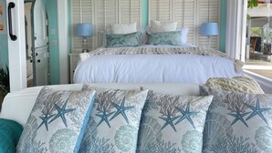 A bedroom with a bed, two bedside tables, a nightstand, a window with a view, and a door. - 100' of Ocean Frontage at Moonlight Beach (Encinitas)