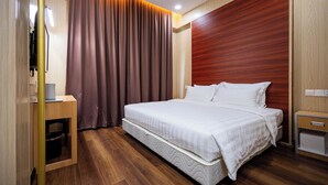 Quarto de hotel moderno com uma cama grande, piso de madeira, cabeceira de madeira, mesa de cabeceira e TV integrada.