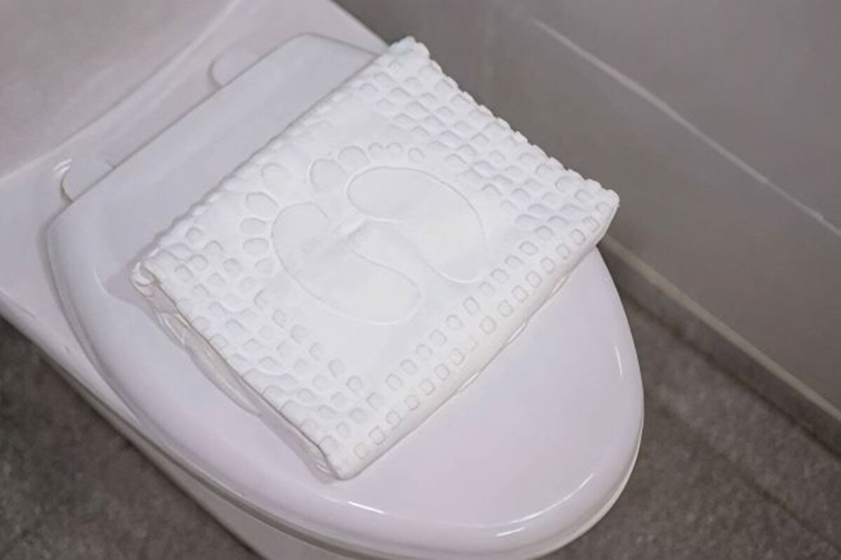 Des toilettes blanches avec un abattant texturé.