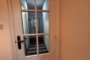 Uma porta com painel de vidro e puxador de metal.