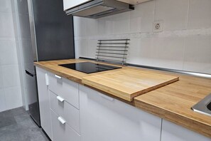 A modern kitchen with a wooden countertop, built-in oven, and white cabinetry.