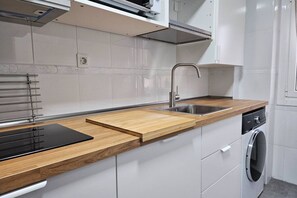 Een moderne keuken met een houten aanrecht, een roestvrijstalen spoelbak en een inbouw vaatwasser.
