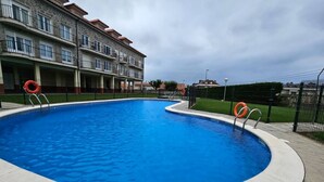 A swimming pool with a curved edge, surrounded by a concrete deck. - C12A01 Charming home with a pool and garage by R2R (Suances)