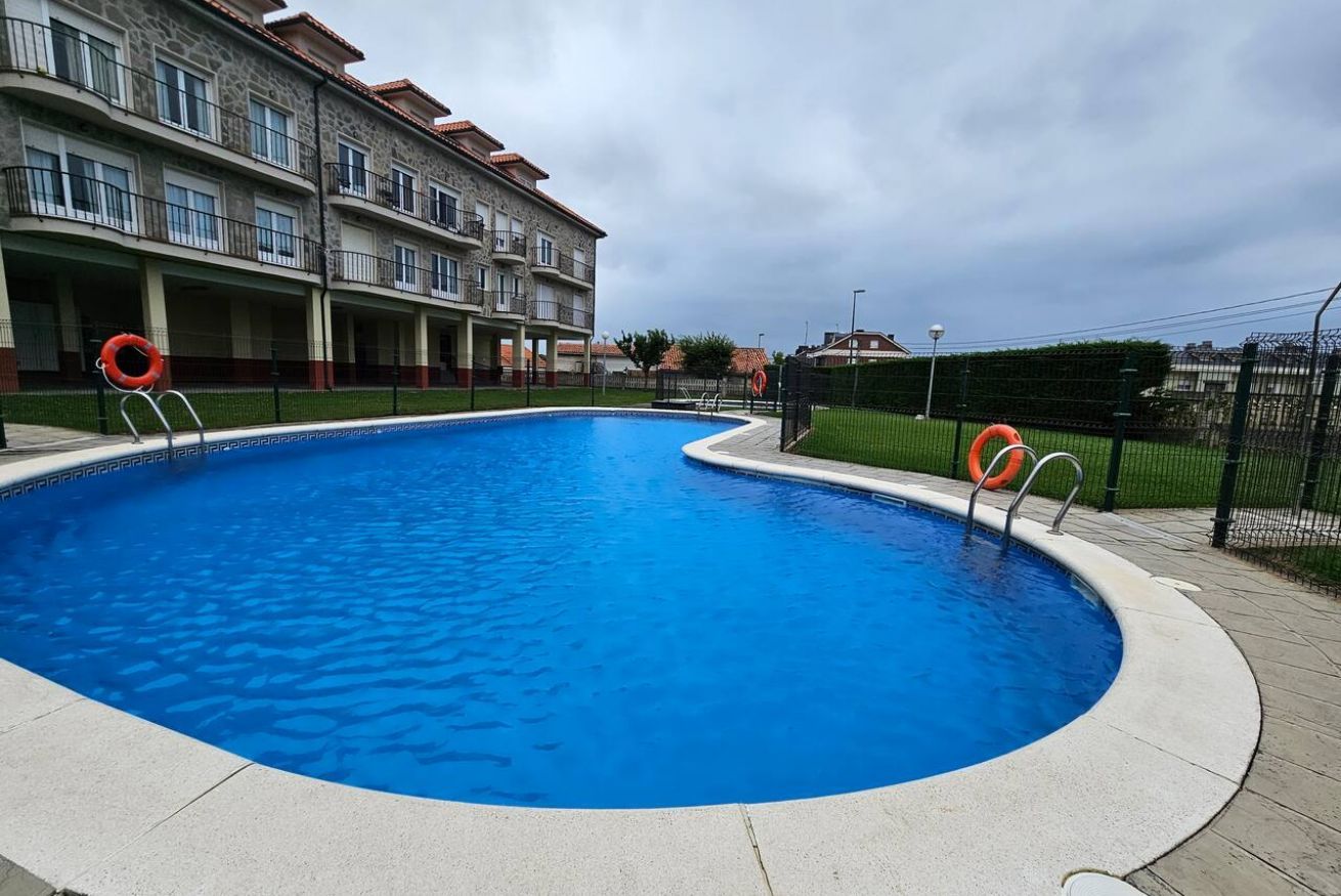 A swimming pool with a curved edge, surrounded by a concrete deck.