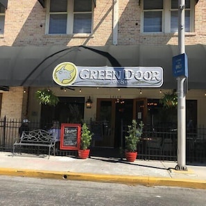 Fachada de una tienda con un letrero que dice "GREEN DOOR" y un logotipo de una puerta verde con un caballo blanco.