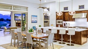 A modern kitchen with a central island, bar stools, and pendant lighting.