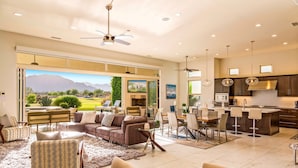 A spacious living area with a large window, a dining area, and a kitchen with modern appliances.