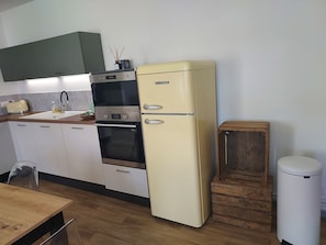 Una cucina con frigorifero bianco, forno a incasso, tostapane e pensili in legno.