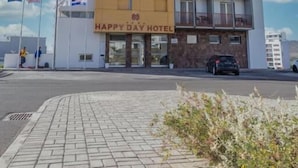 A multi-story hotel with a sign reading "Happy Day Hotel". - Happy Day Hotel (Praia)