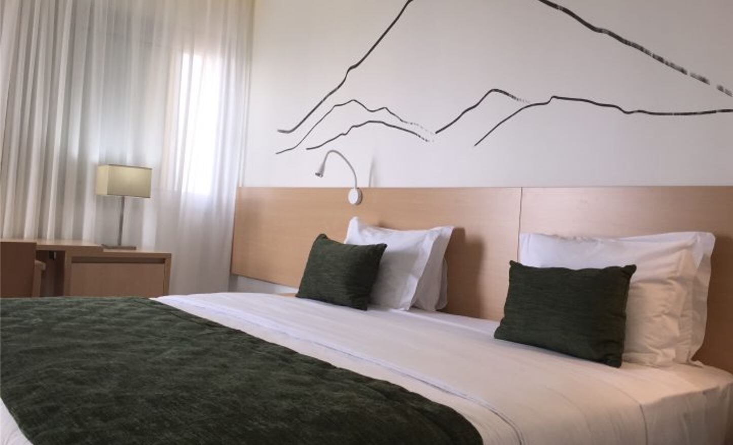 Une chambre d’hôtel avec un lit, une table de chevet, une lampe et une œuvre d’art murale.