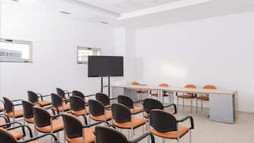 A conference room with rows of chairs, a large table, and a flat-screen TV.