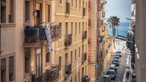 A narrow street lined with multi-story buildings, some with balconies, leading to a beach. - 2 bed apartment in Barceloneta steps from the beach (Barcelona)