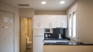 A compact kitchen with white cabinets, a microwave, a kettle, and a window. - 2 bed apartment in Barceloneta steps from the beach (Barcelona)