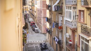 A narrow urban street with parked scooters and a white van.